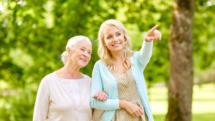 junge Frau mit einer älteren Dame, die möglicherweise an Demenz leidet, bei einem Sparziergang