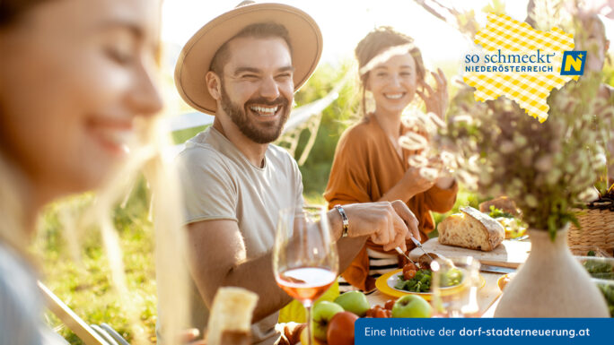 Junge und fröhliche Menschen beim festlichen Mittagessen im Grünen