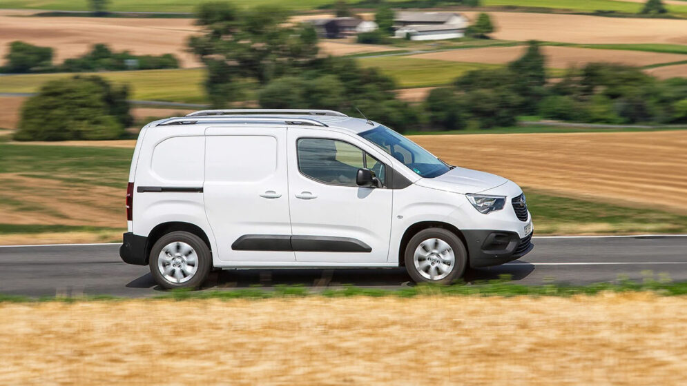 weißer Opel Combo Cargo electric fährt auf der Straße, die durch abgeerntete Felder führt