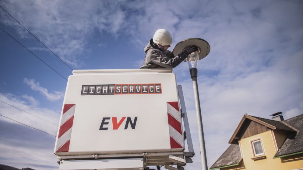 Ein Mann auf einer Hebebühne, auf der EVN zu lesen ist, kontrolliert eine Straßenlaterne.