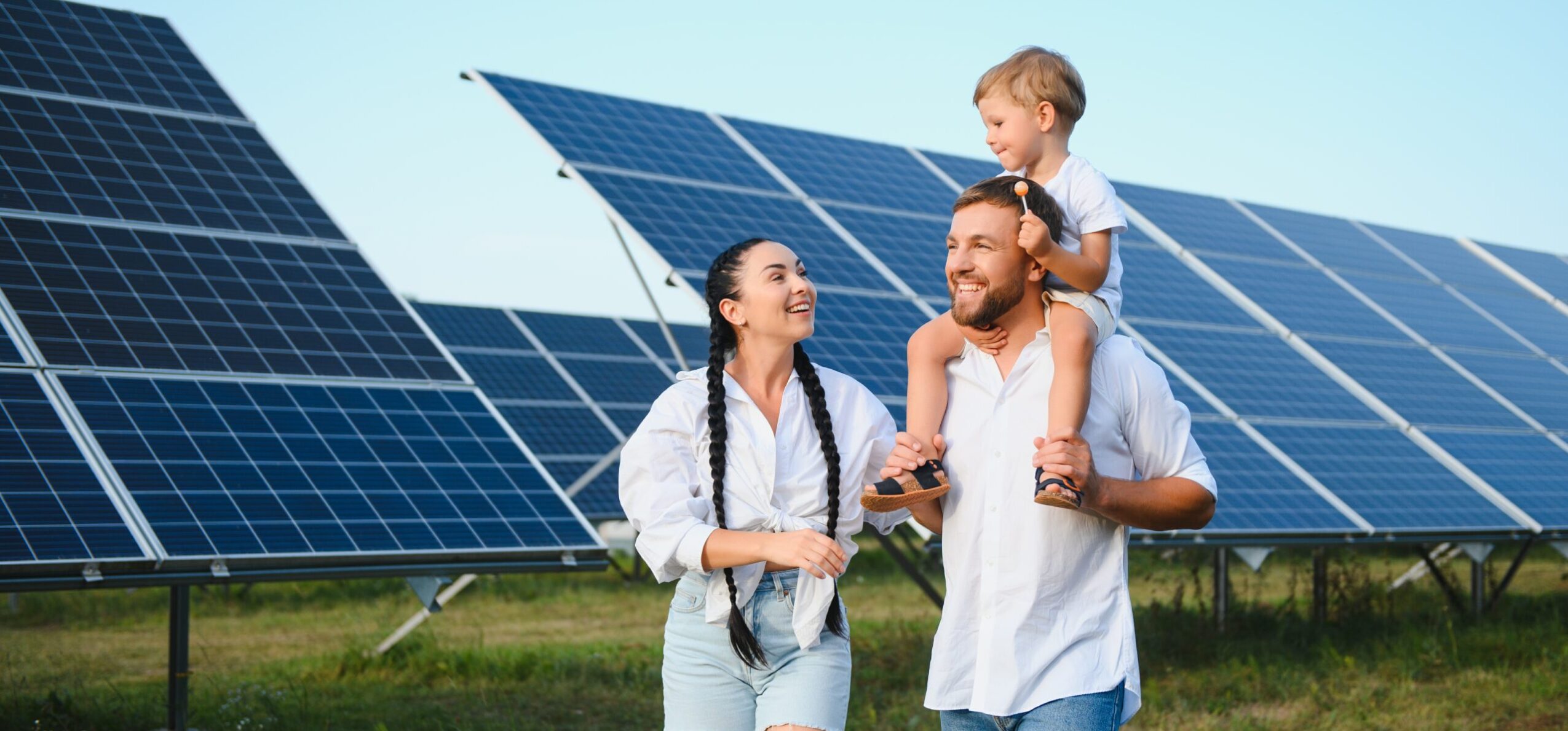 Begeisterter Vater zeigt das Potenzial alternativer Energie. Moderne Familie betrachtet die neue Solaranlage, die sie gekauft hat. Seitenansicht von glücklichen Eltern und interessiertem Kind neben den Solarpanels.