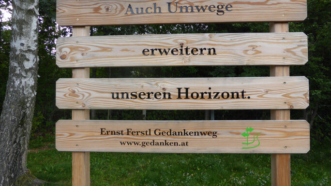 Das Foto zeigt ein der Taflen entlang des Ernst-Ferstl-Gedankenweges mit dem Spruch "Auch Umwege erweitern unseren Horizont".