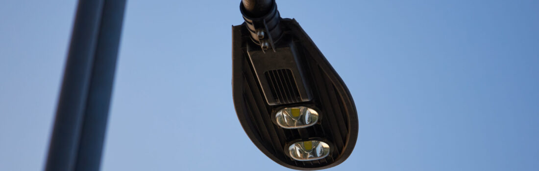 Moderne Straßenbeleuchtung mit zwei LEDs auf schwarzem Mast, Stadtentwicklung, Stadtpark, blauer Himmel.
