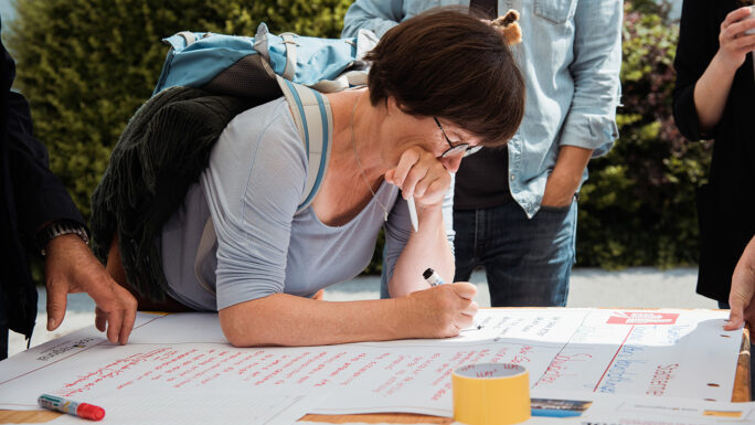 Frau in Work-Shop-Situation schreibt auf einem Flipchart