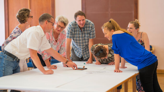 Menschen unterschiedlicher Altersgruppen diskutieren und halten die Ergebnisse auf einem Plakat fest.