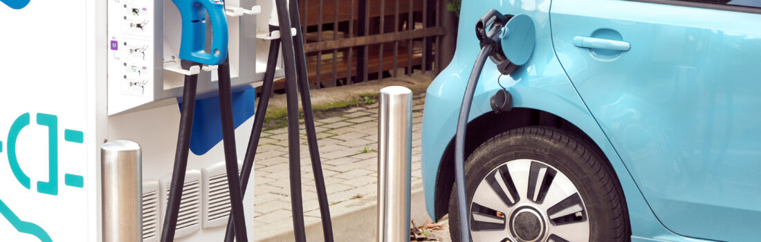Ein Elektroauto an einer Ladestation auf der Straße, mit angeschlossenem Ladekabel.